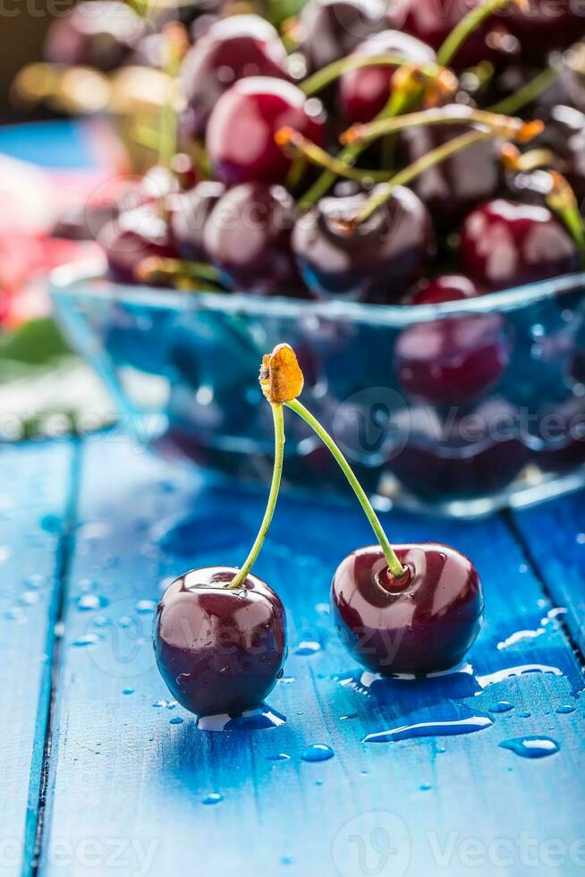 Ripe sweet cherries on blue woden table with water drops photo