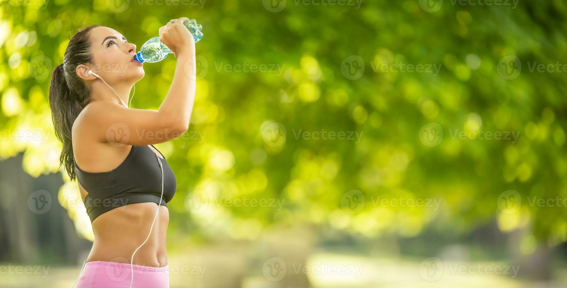 Female runner hydrates after finishing a running race, drinks water from a bottle. photo