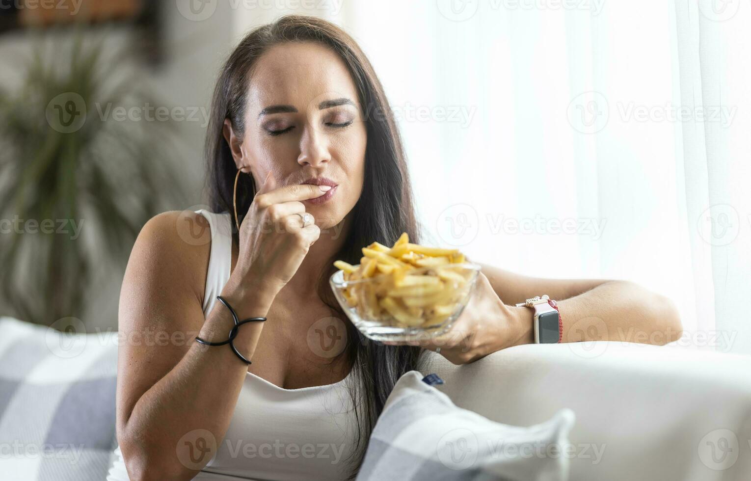 Woman licks her finger enjoying the taste of crispy and soft fresh french fries photo