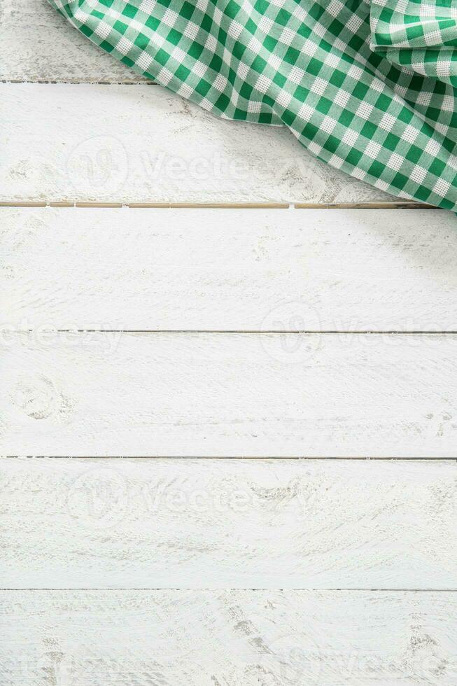 Green checkered kitchen tablecloth on wooden table photo