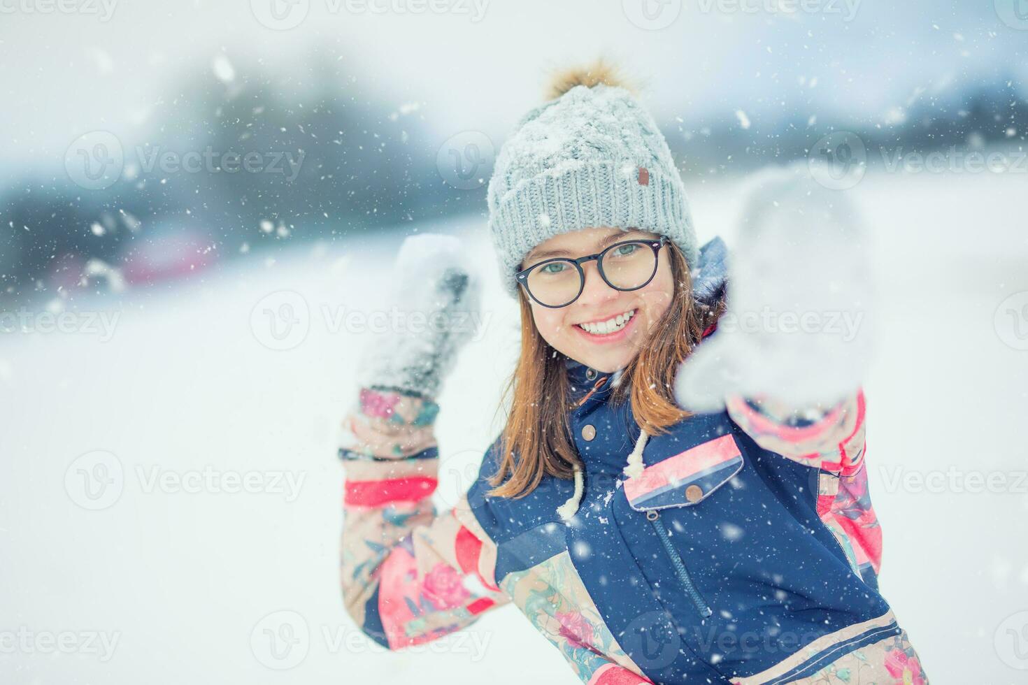 Winter happy teen girl  playing in snow throwing snowball photo