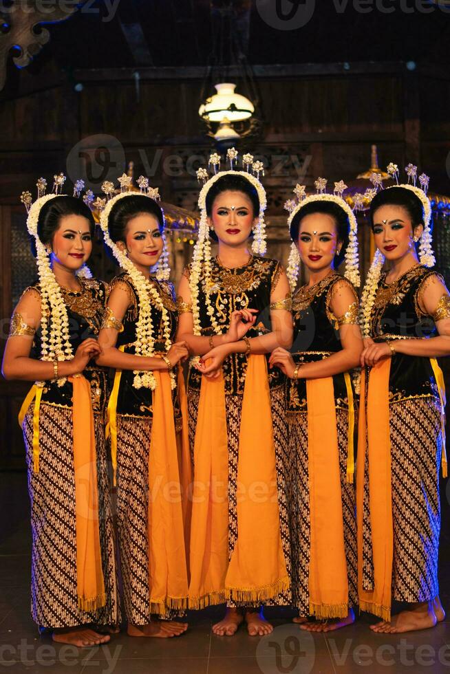 a group of Javanese dancers standing with their friends while wearing yellow costumes and shawls photo