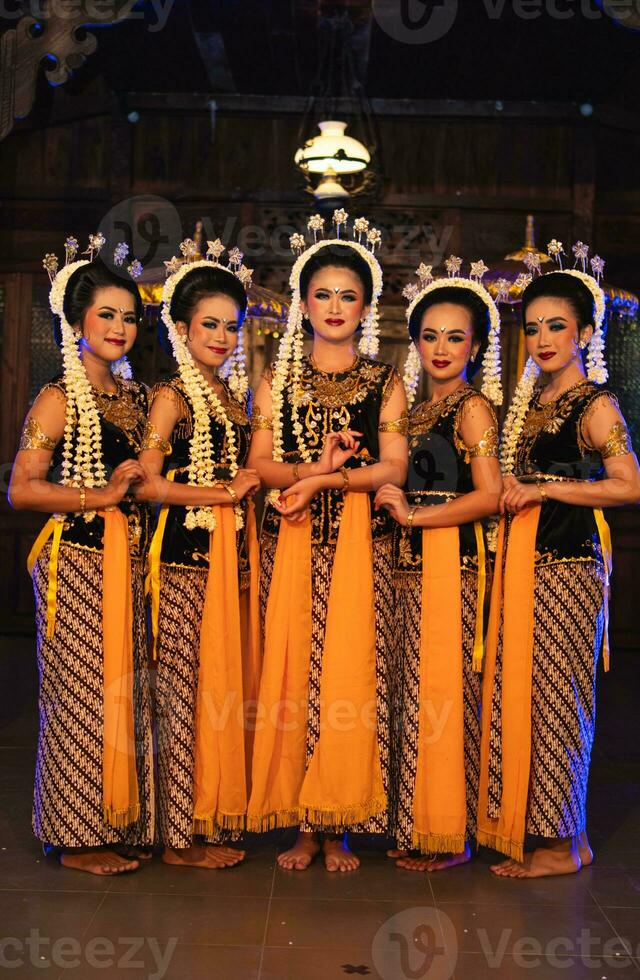 a group of Javanese dancers standing with their friends while wearing yellow costumes and shawls photo