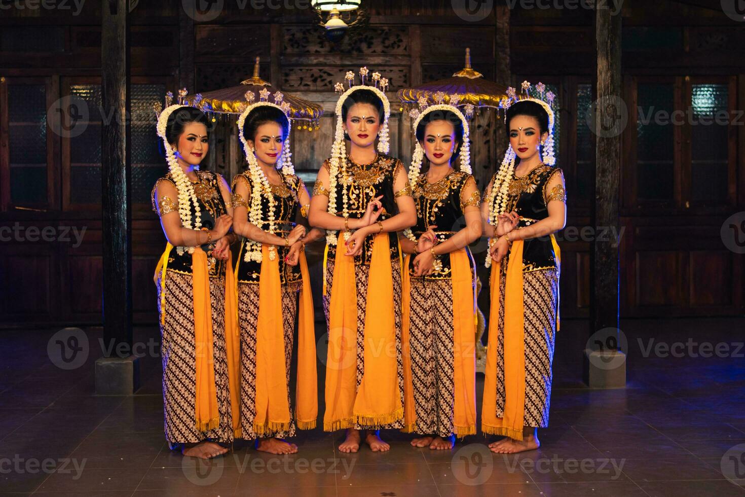 a group of Javanese dancers standing with their friends while wearing yellow costumes and shawls photo