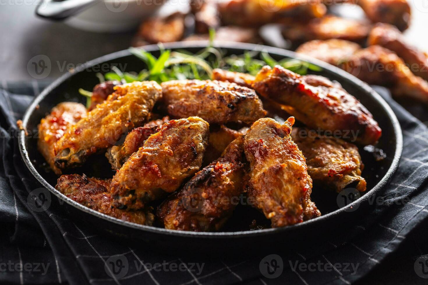 Chicken wings barbeque in a cast iron baking dish with BBQ sauce and rosemary photo