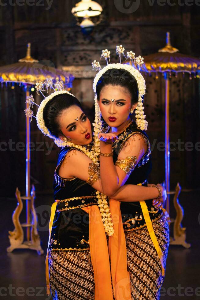 two Javanese dancers in yellow scarves taking pictures with ridiculous faces photo