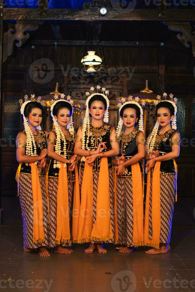 un grupo de javanés bailarines en pie con su amigos mientras vistiendo amarillo disfraces y chales foto