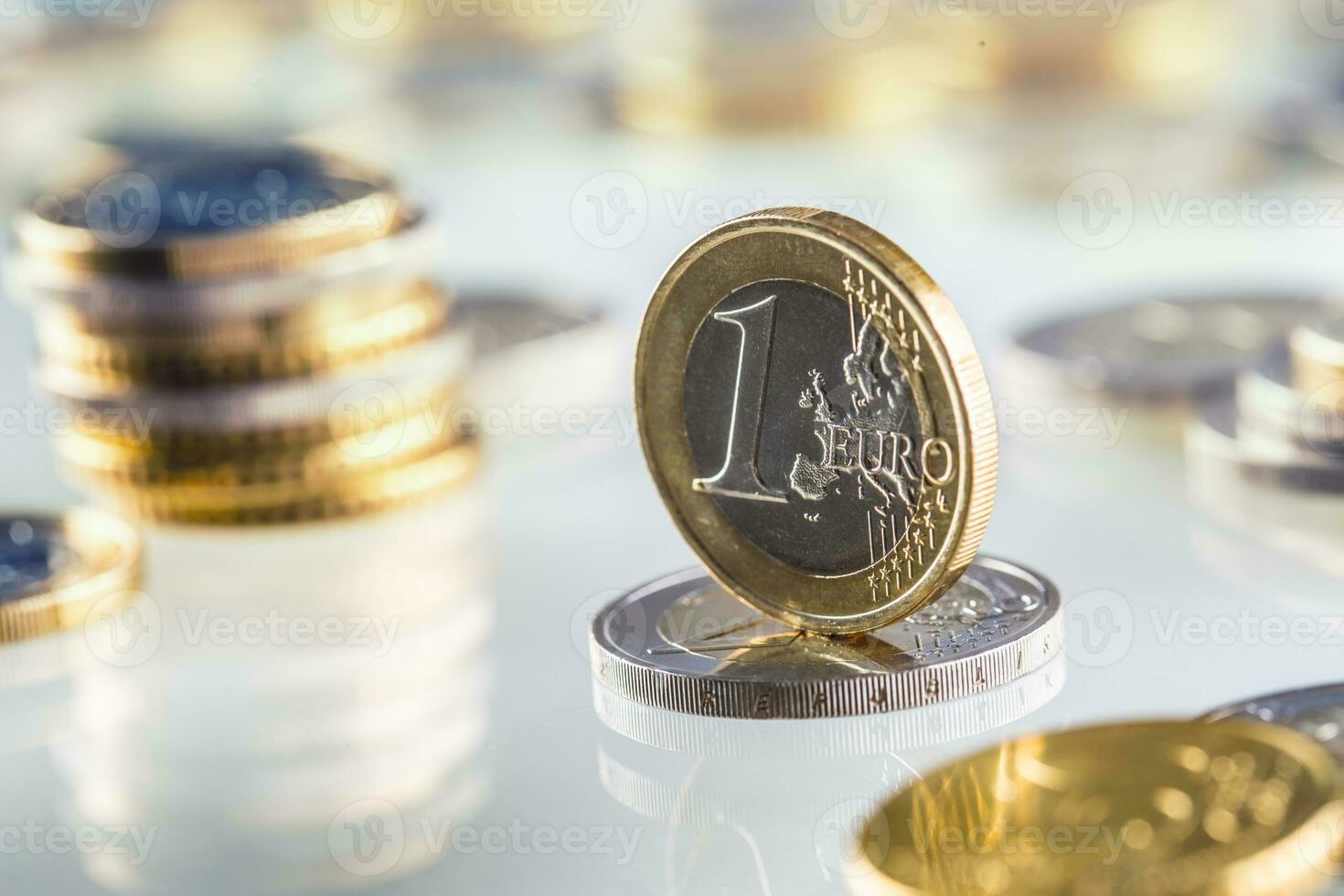 Euro coin balances on another coin and several loose coins photo
