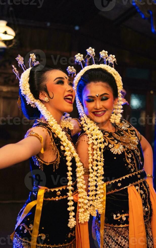 two Javanese dancers in yellow scarves taking pictures with ridiculous faces photo