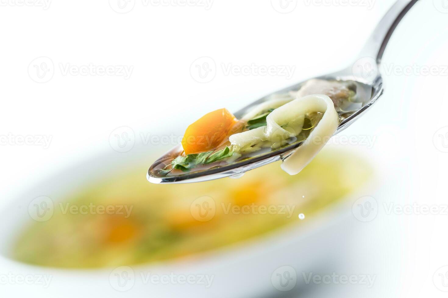Spoon full of chicken or beef soup with noodles carrot and herbs photo