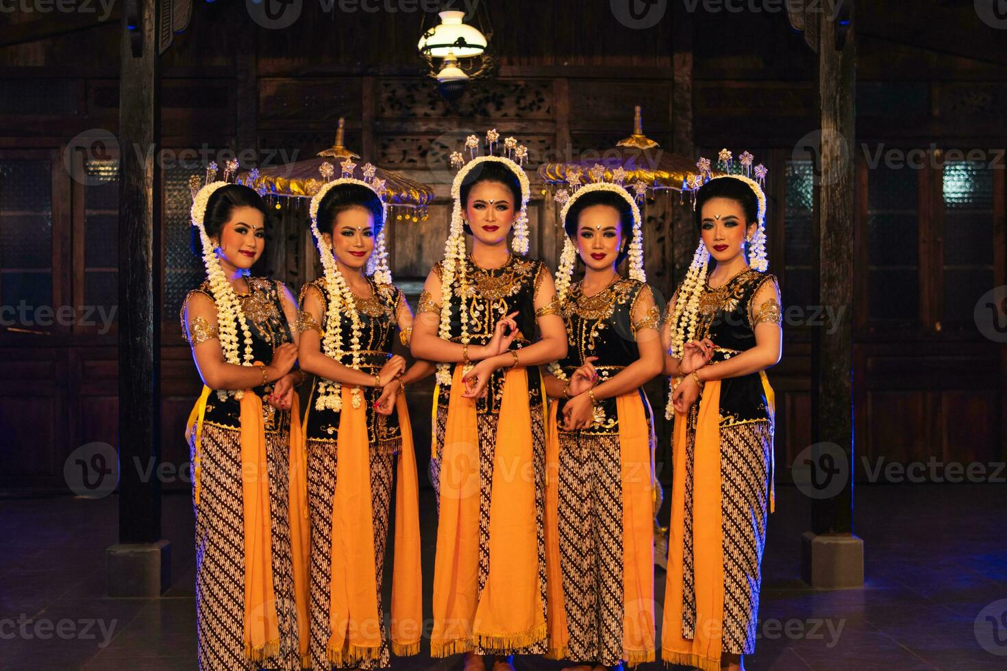 a group of Javanese dancers standing with their friends while wearing yellow costumes and shawls photo