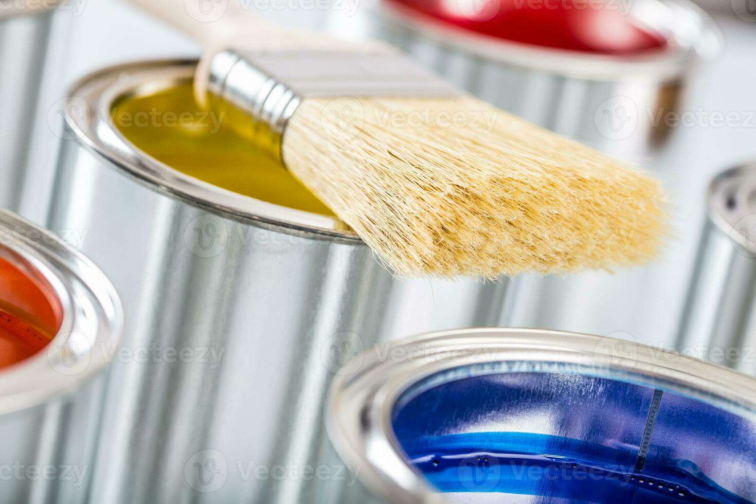 Close-up brush lying on multicolored paint cans. photo