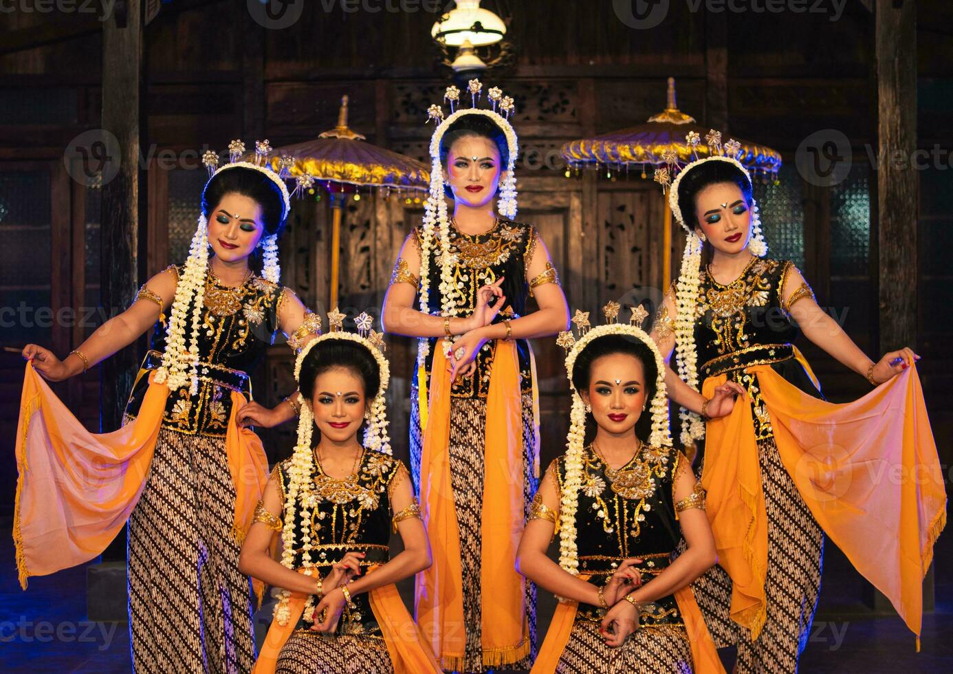 a group of Javanese dancers poses dancing with their friends while taking pictures on the stage photo