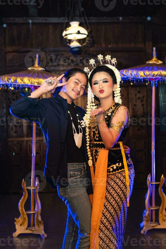 a Javanese dancer taking pictures with fans on stage photo