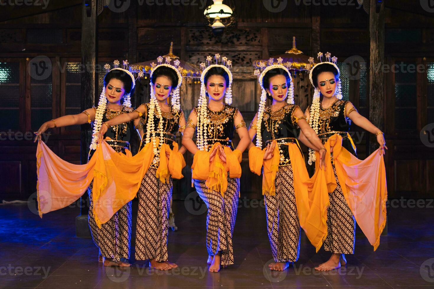 a group of Javanese dancers holding yellow shawls while dancing on stage photo