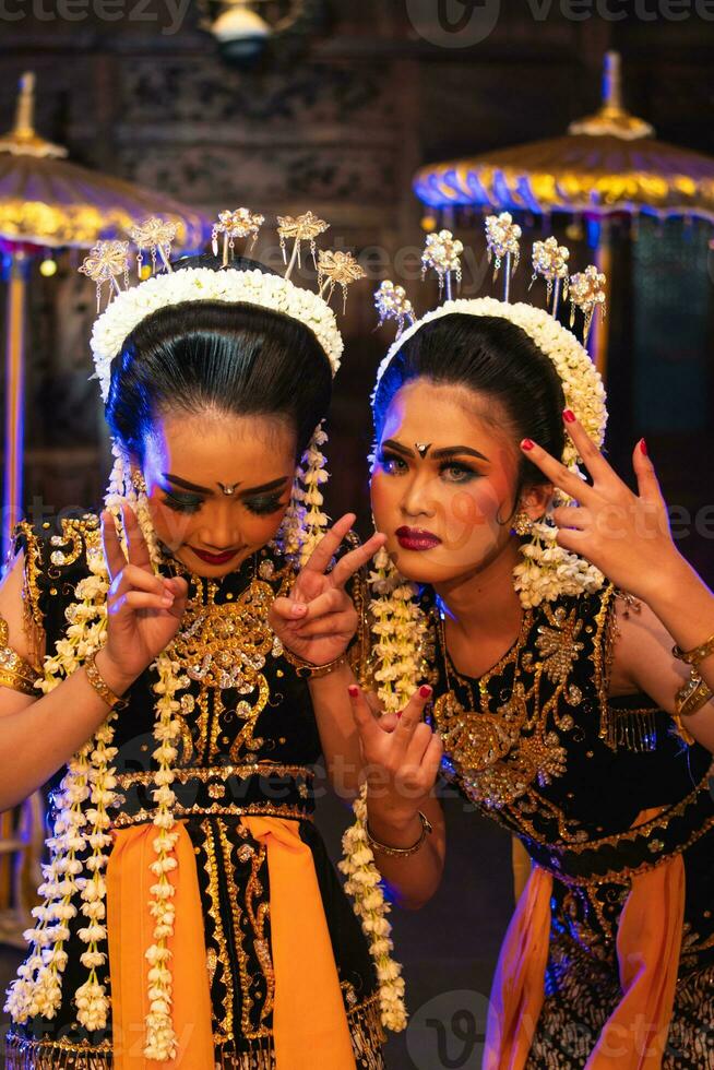two Javanese dancers in yellow scarves taking pictures with ridiculous faces photo