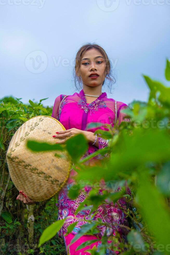 un indonesio mujer en un rosado vestir participación un bambú sombrero en su manos foto