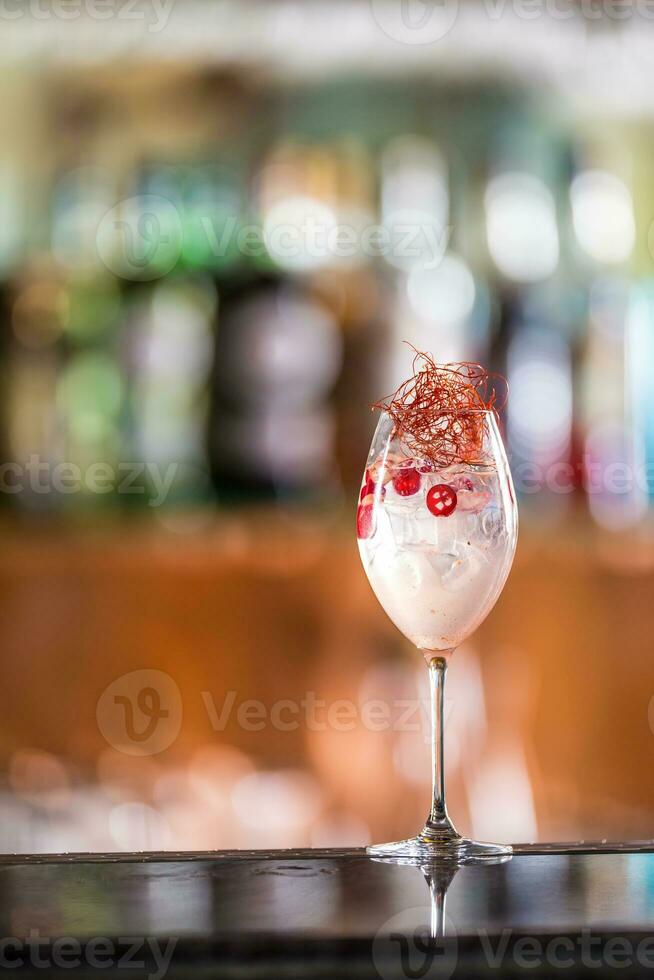 Gin tonic cocktails in wine glass with chili on bar counter in pup or restaurant photo