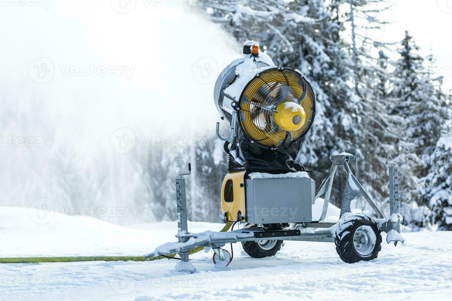 Snow cannon gun or machine sprays water and snowes a ski or cross-country track photo