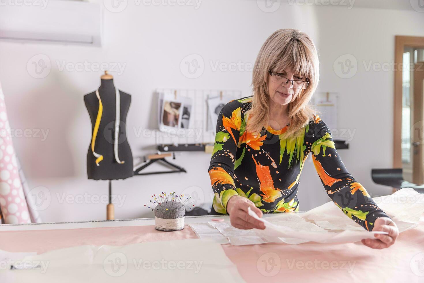 Cutting of fabric by a tailor in the workshop based on the paper template photo