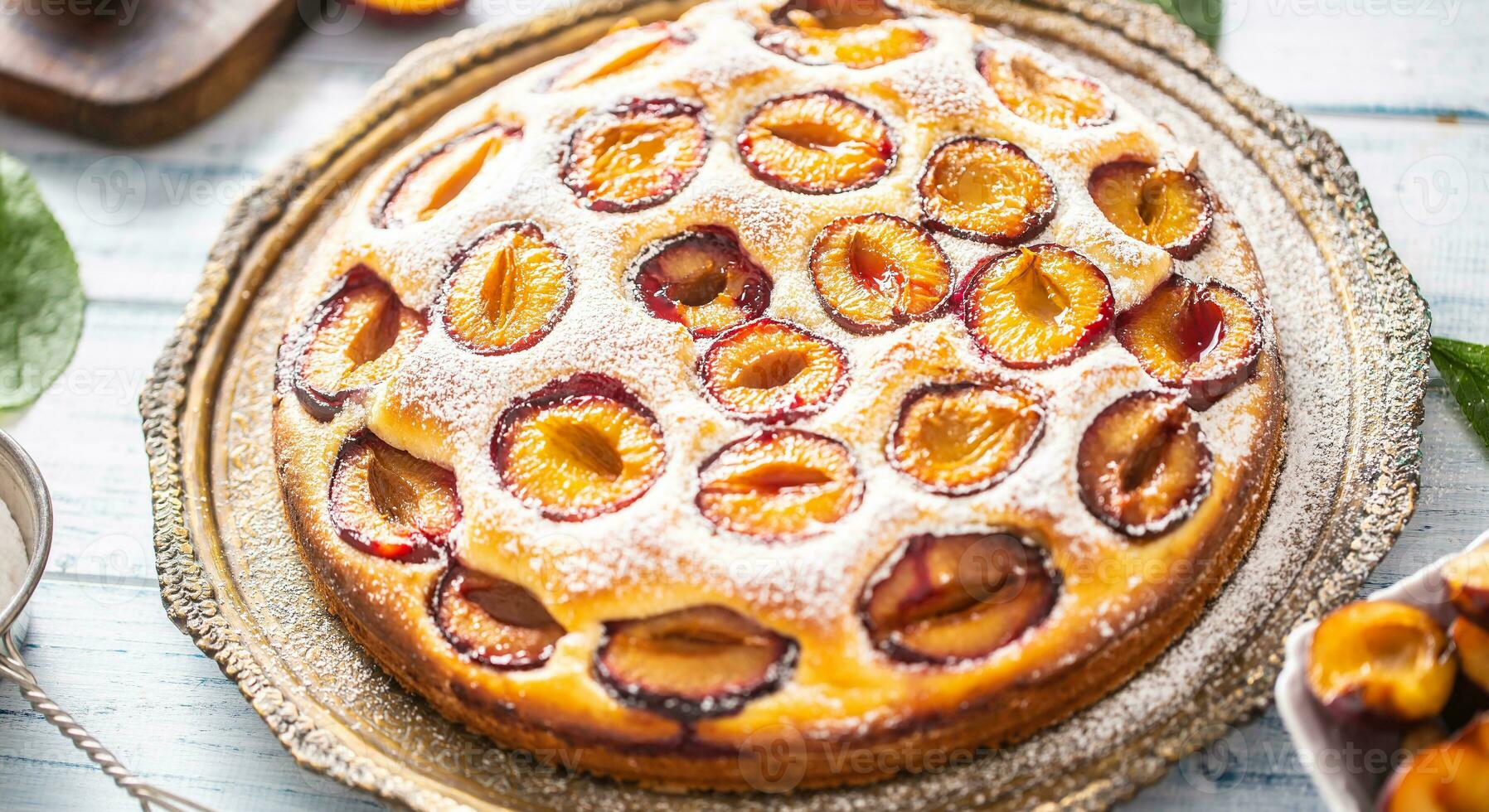 Homemade plum cake in vintage plate on wooden table. Plums pie with sugar powder photo