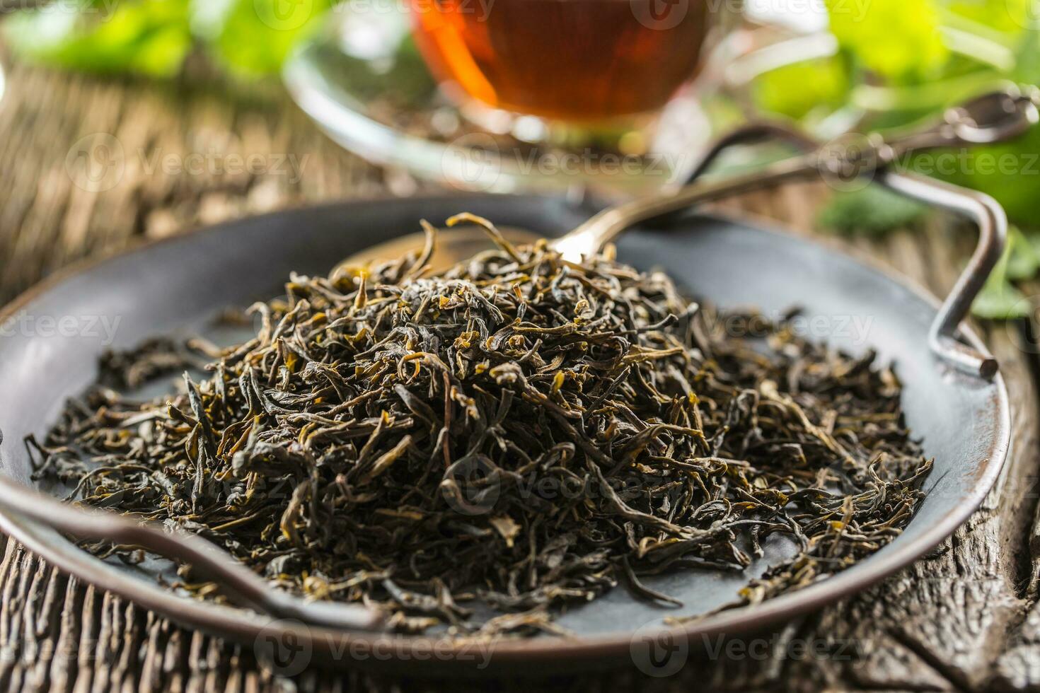 Dried tea leaves in bowl on rustic wooden table photo