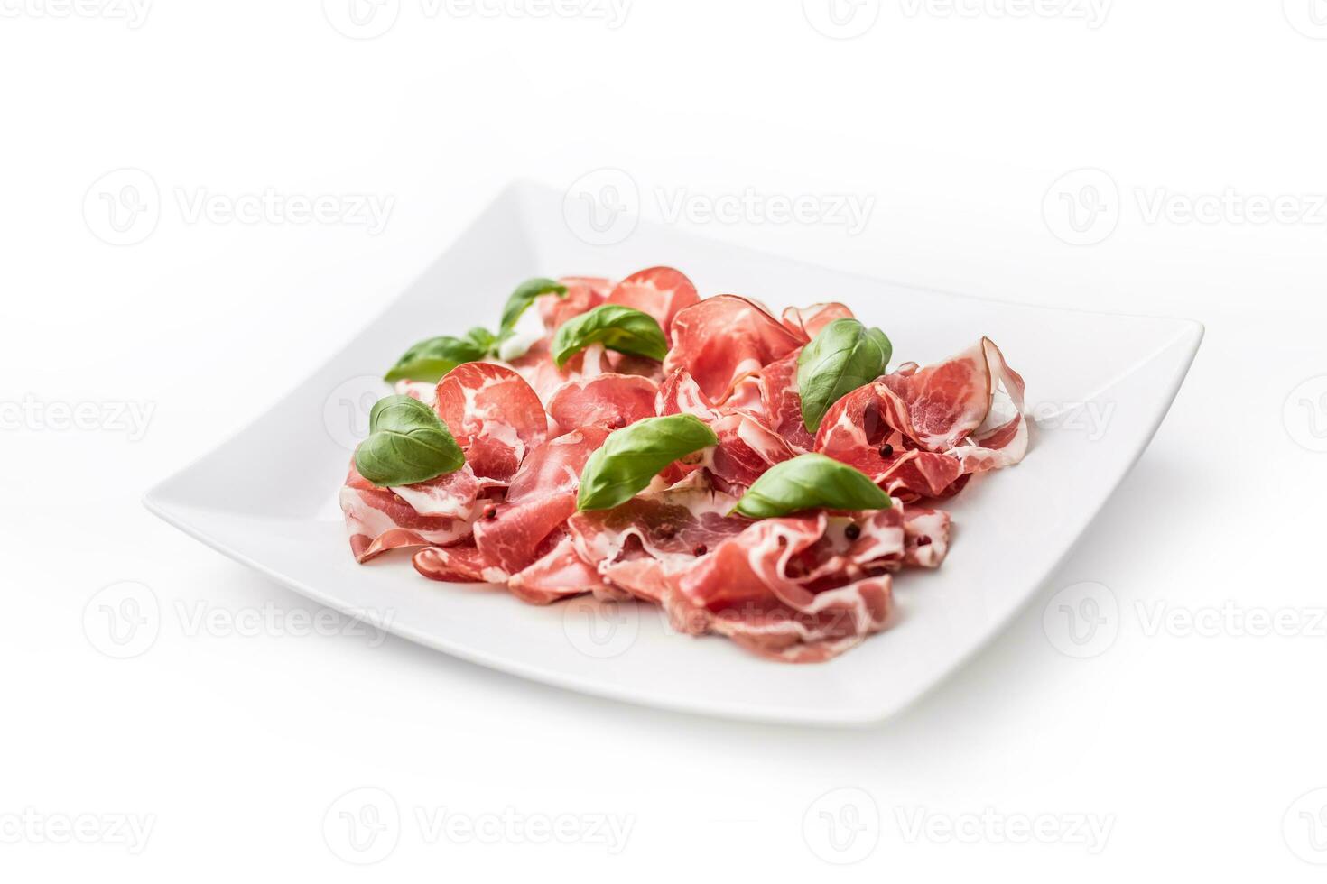 Prosciutto. Curled slices of delicious Italian Prosciutto with basil photo