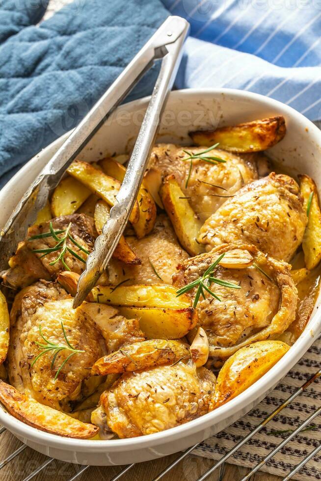 Chicken legs roasted with american potatoes in baking dish photo