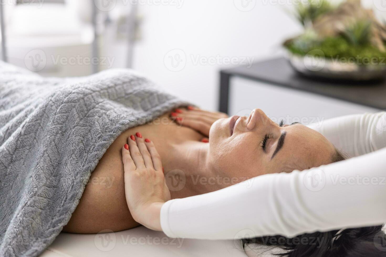Woman lies with closed eyes as masseuse rubs her shoulders to ease work-related accumulated tension photo