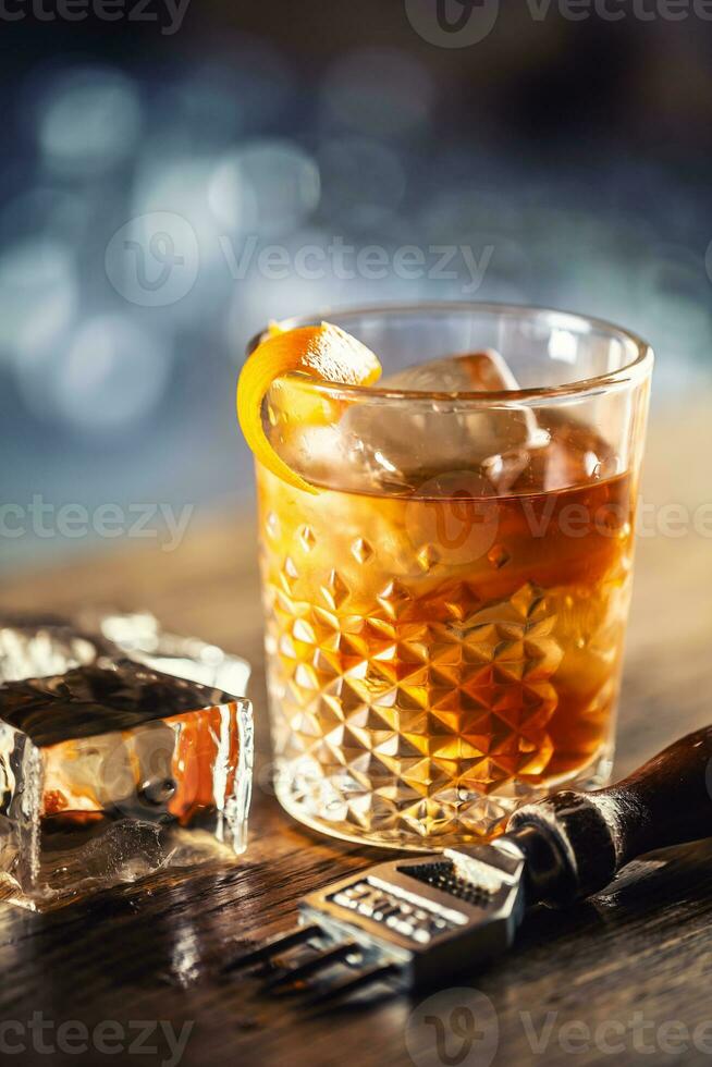 Old fashioned rum drink on ice with orange zest garnish photo