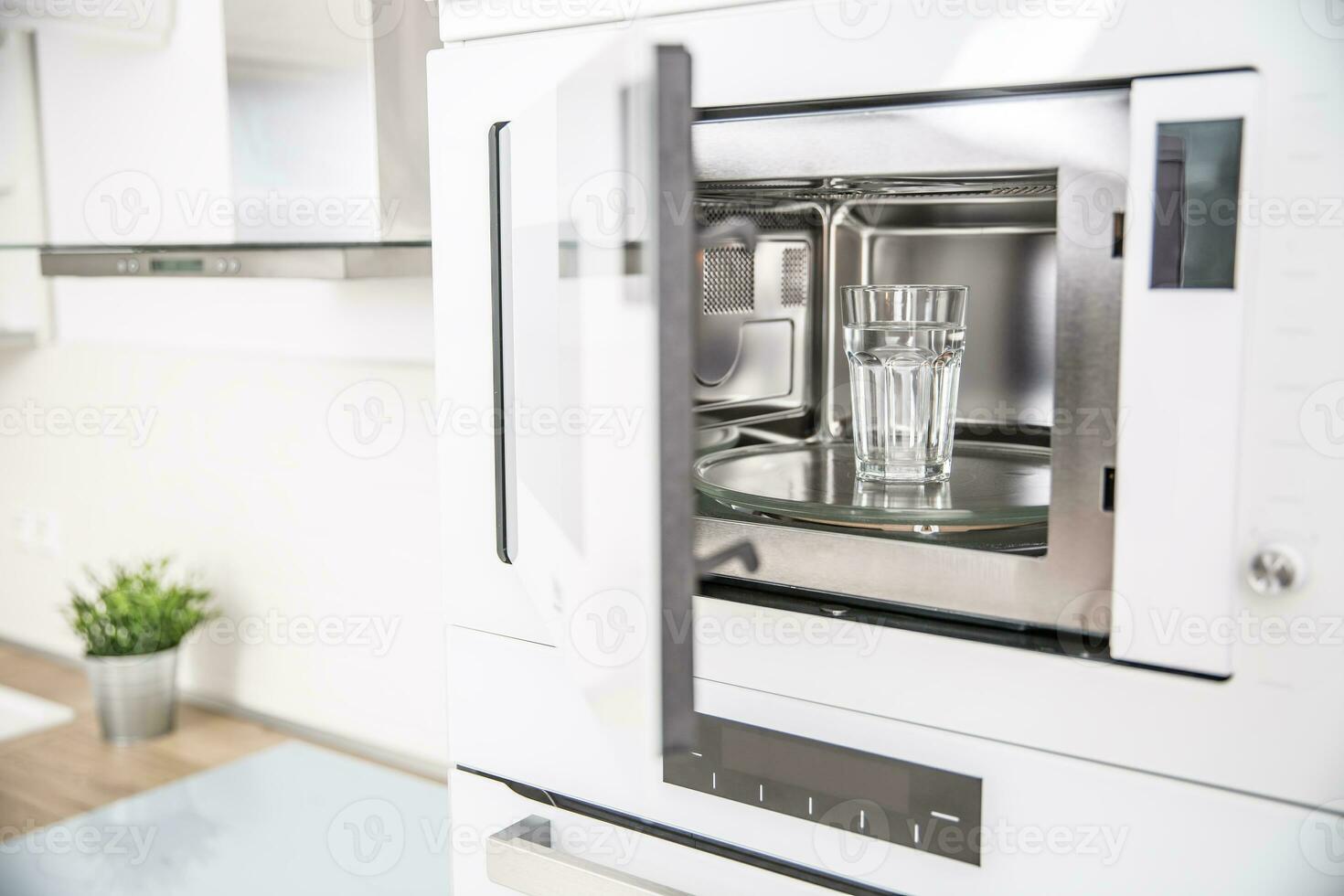 Built-in microwave oven  in the kitchen with a cup of pure water photo