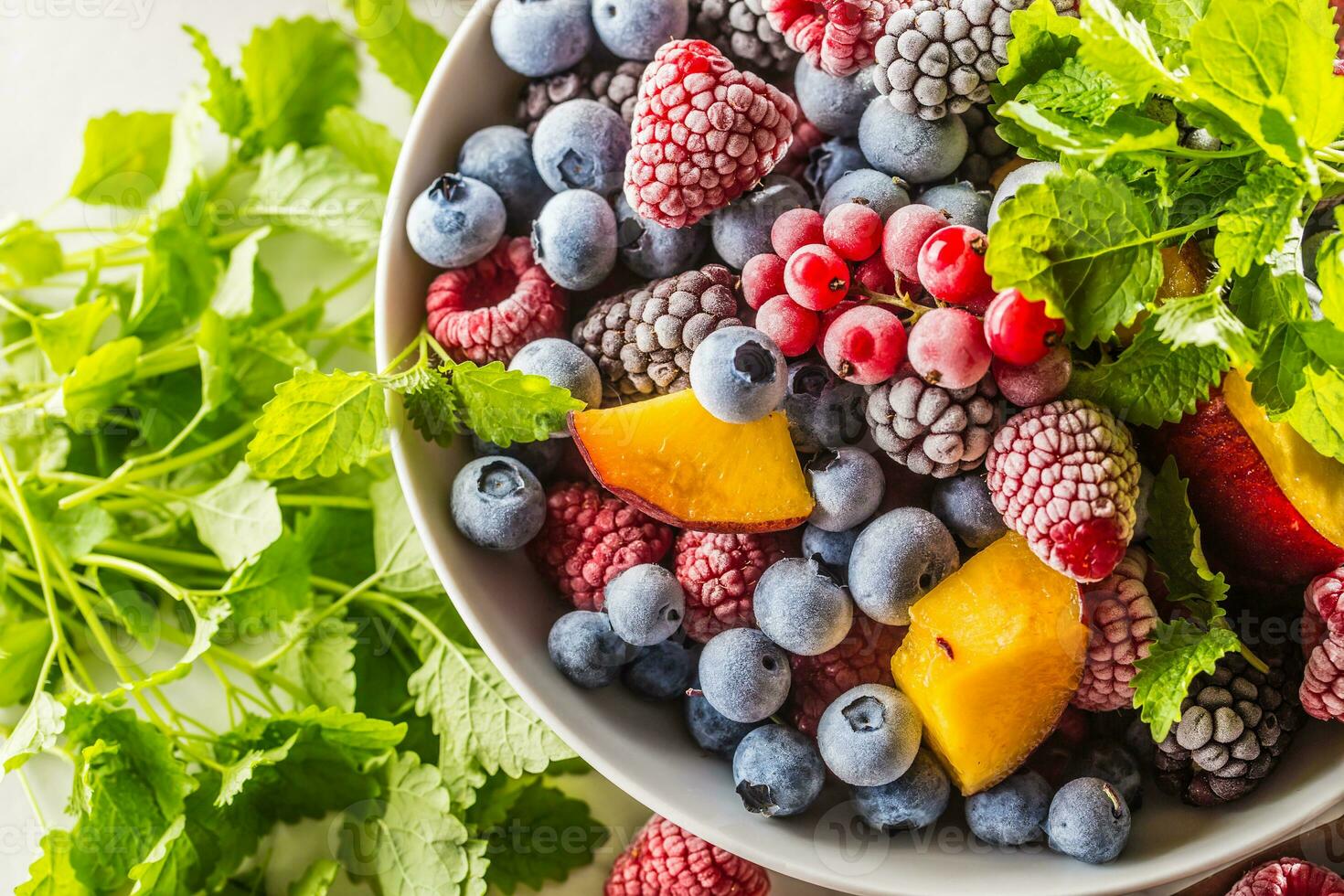 Frozen fruits blueberries blackberry raspberry red currant peach and herbs melissa photo