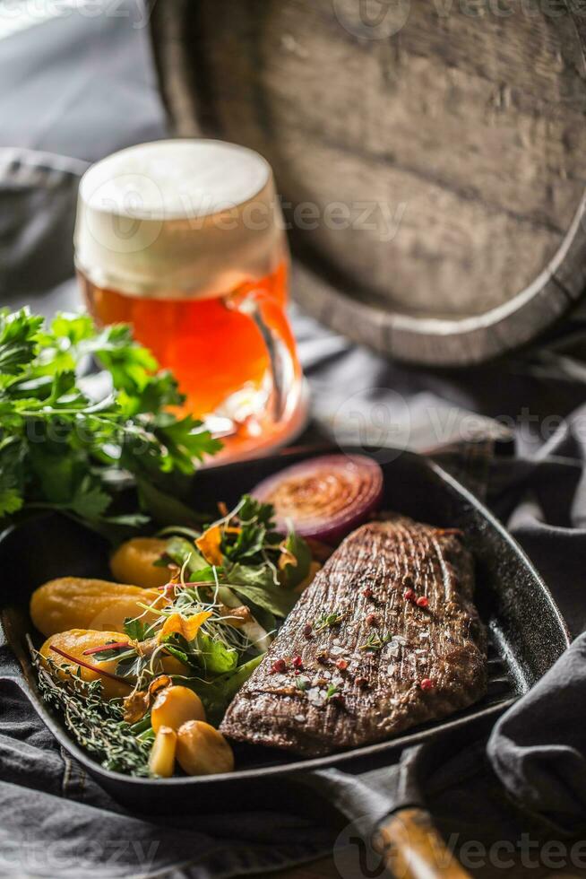 Beef flank steak in grill pan with batata puree garlic herb decoration and draft beer photo