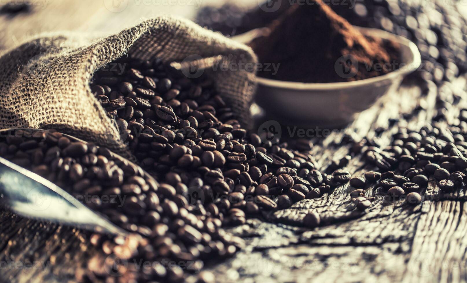 Coffee beans in burlap sack on old wooden table photo