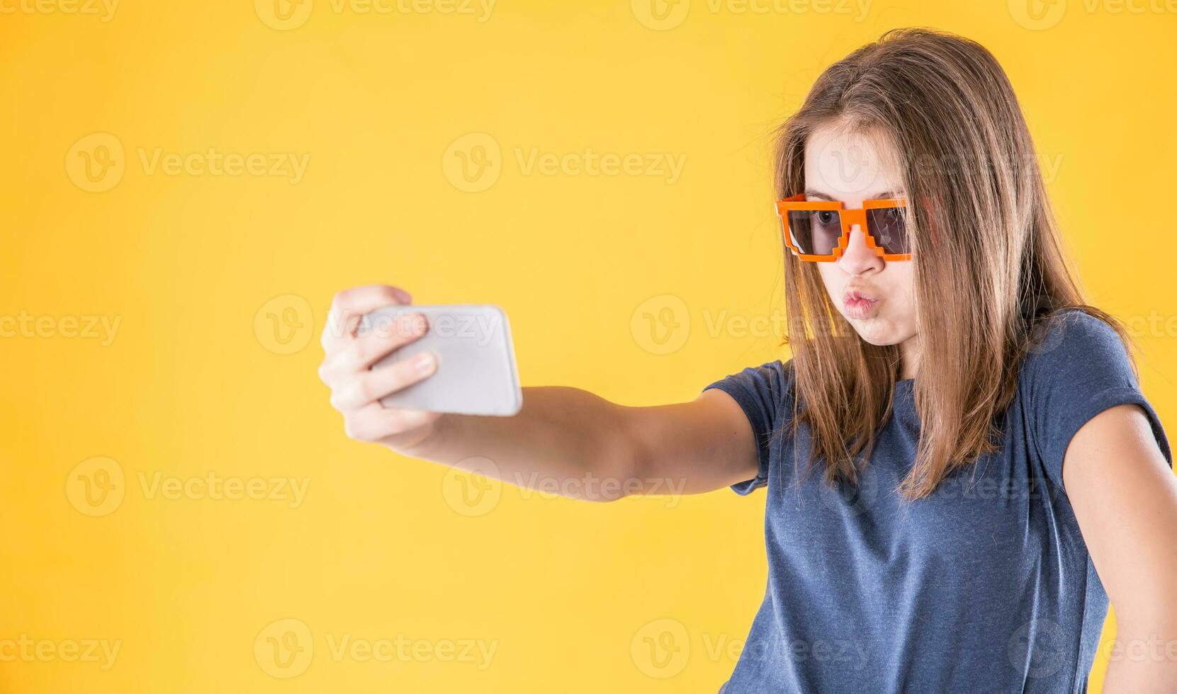 retrato de loco adolescente niña con retro lentes haciendo selfie terminado amarillo antecedentes foto