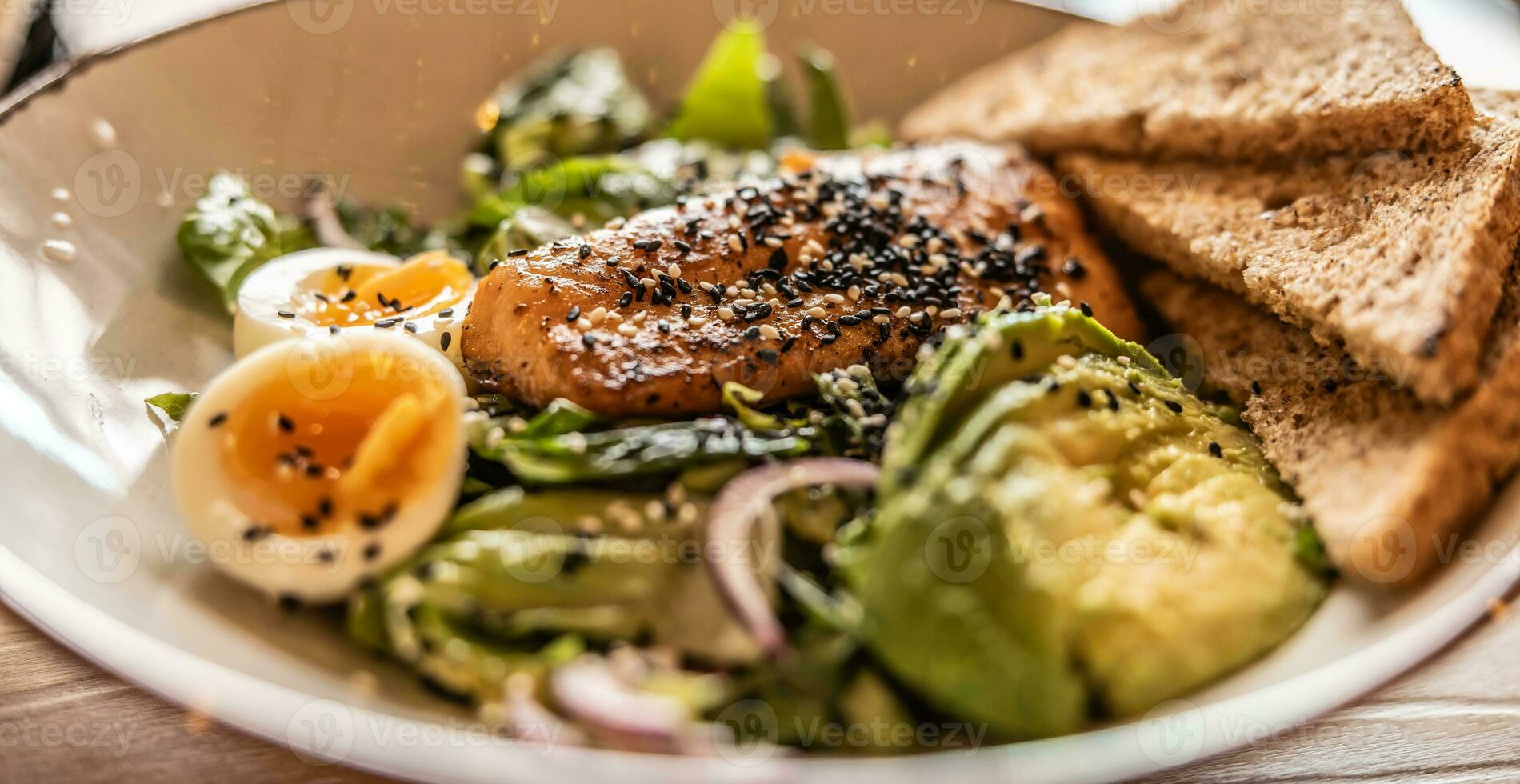 Grilled salmon with sezame is put on fresh leaf salad photo