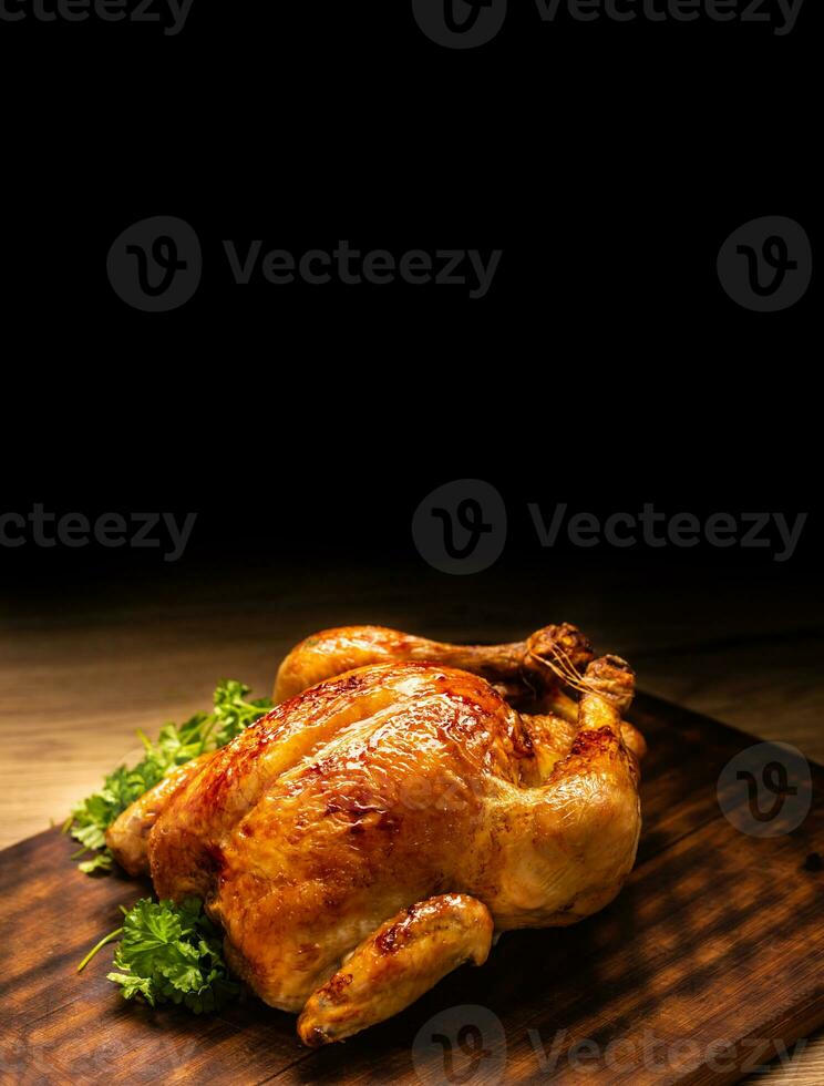 Roasted whole chicken on wooden cutting board photo