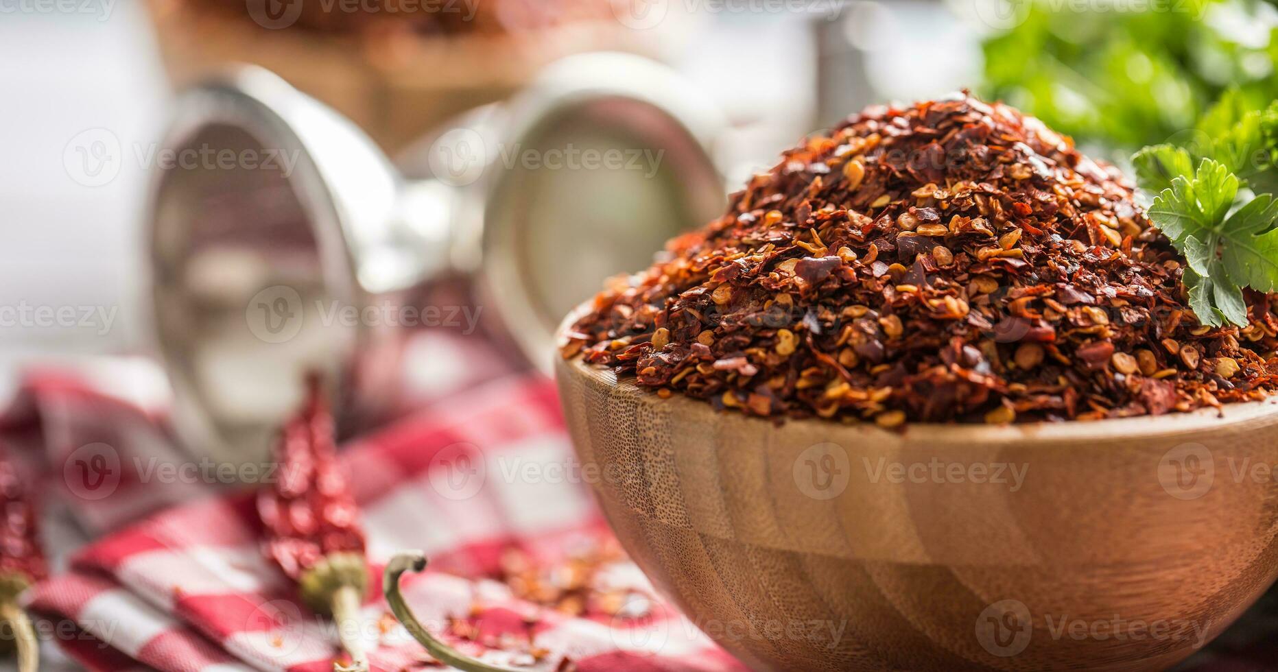 Dried and crushed chili peppers in wooden bowles with parsley herbs photo