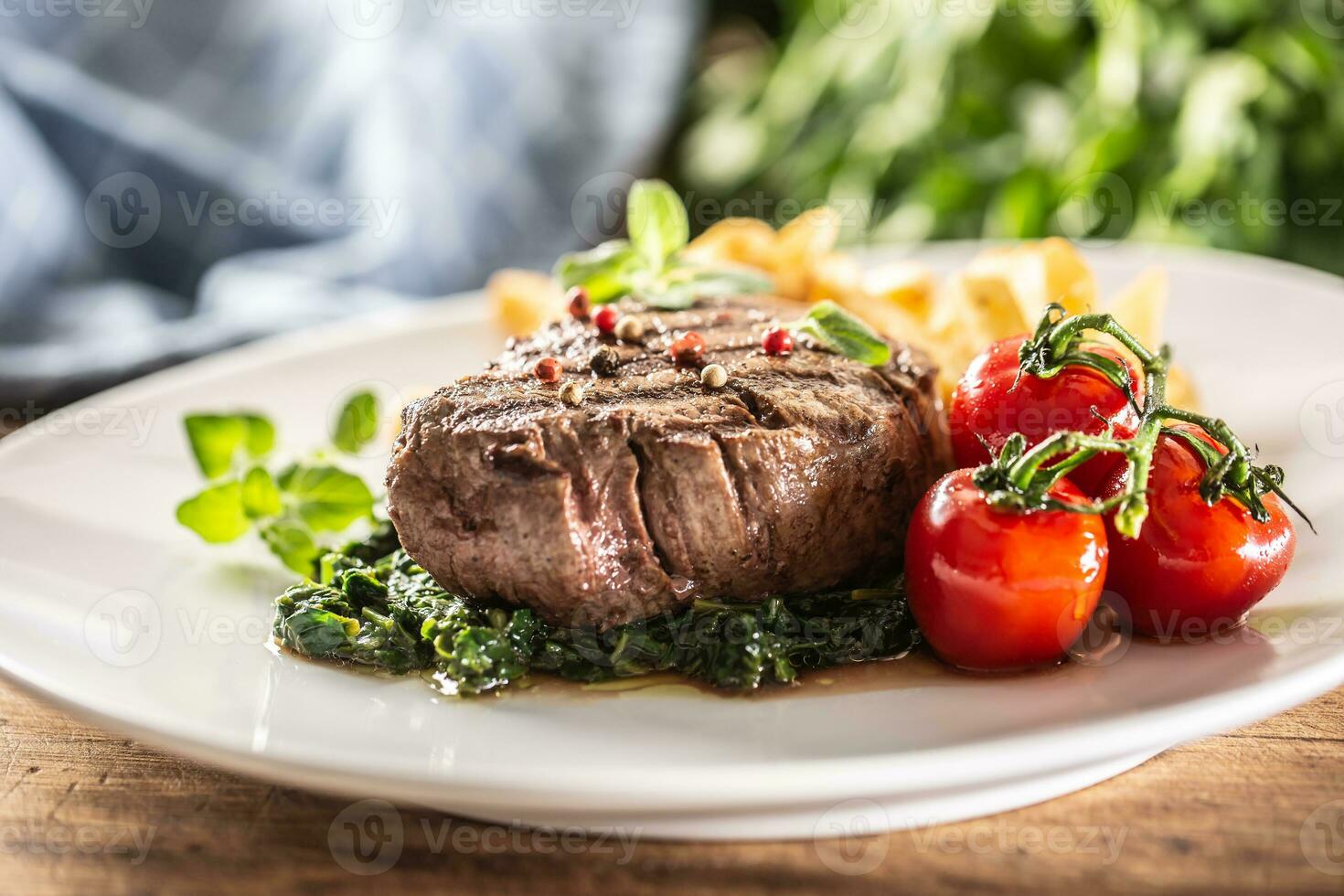 Well-done steak served with veggies on a plate ready to be eaten photo