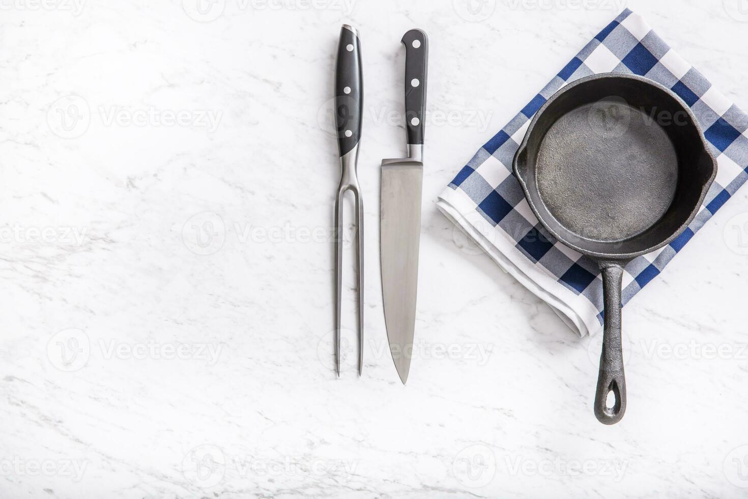 Empty pan on marble table with blue tablecloth knife and fork - top of view photo