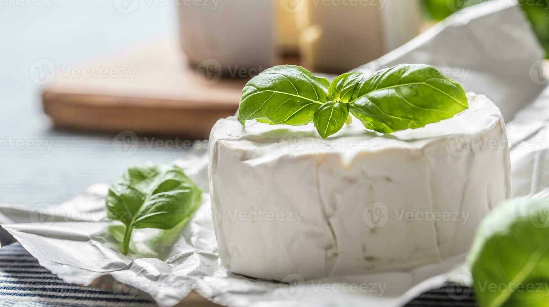 queso Camembert o queso Brie queso con albahaca hojas en mesa foto