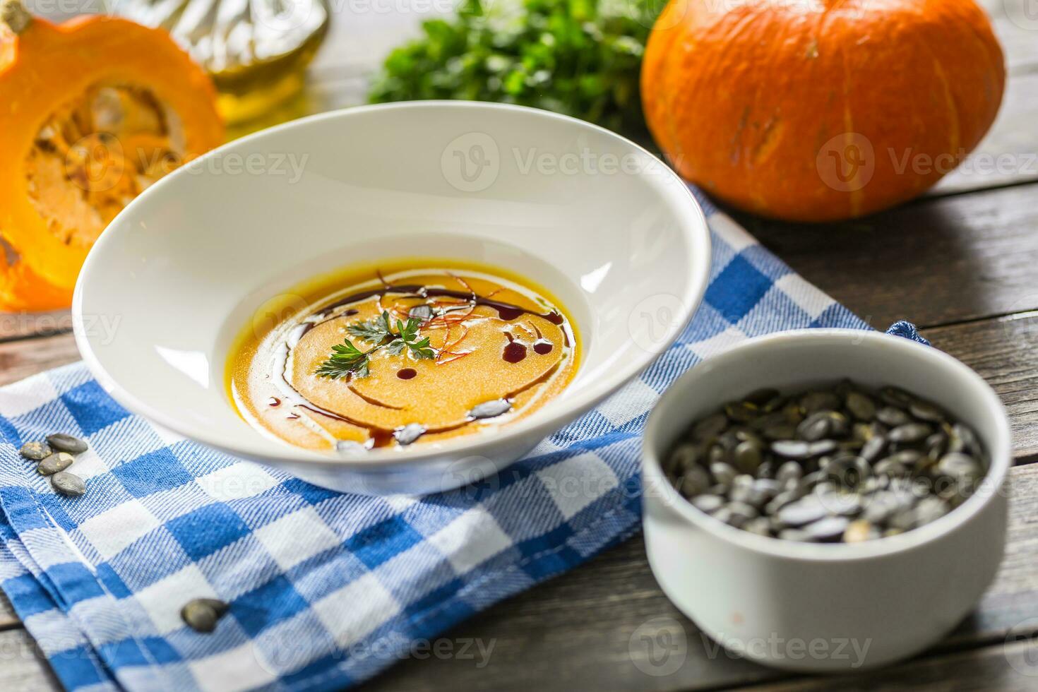 Pumpkin cream soup with seeds and parsley on kitchen table photo