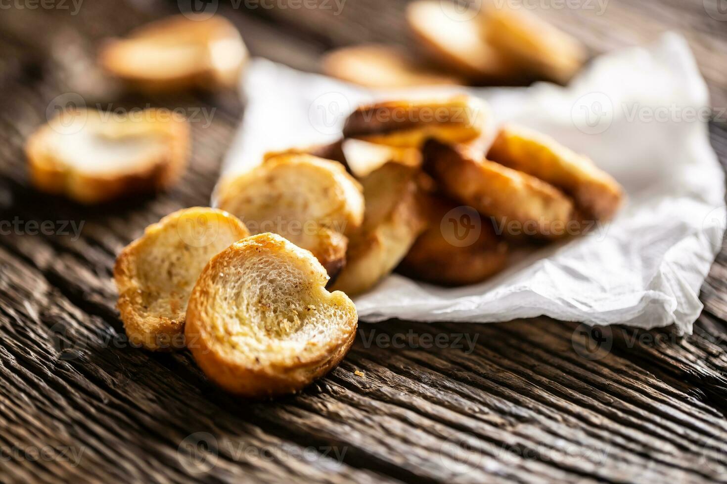 Freshly baked crispy bake rolls with goldish colour served in the paper on a rustic wooden desk photo