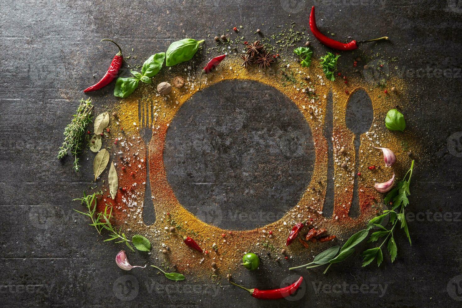 Spices and herbs scattered on the table forming the silhouette of cutlery and a plate. photo