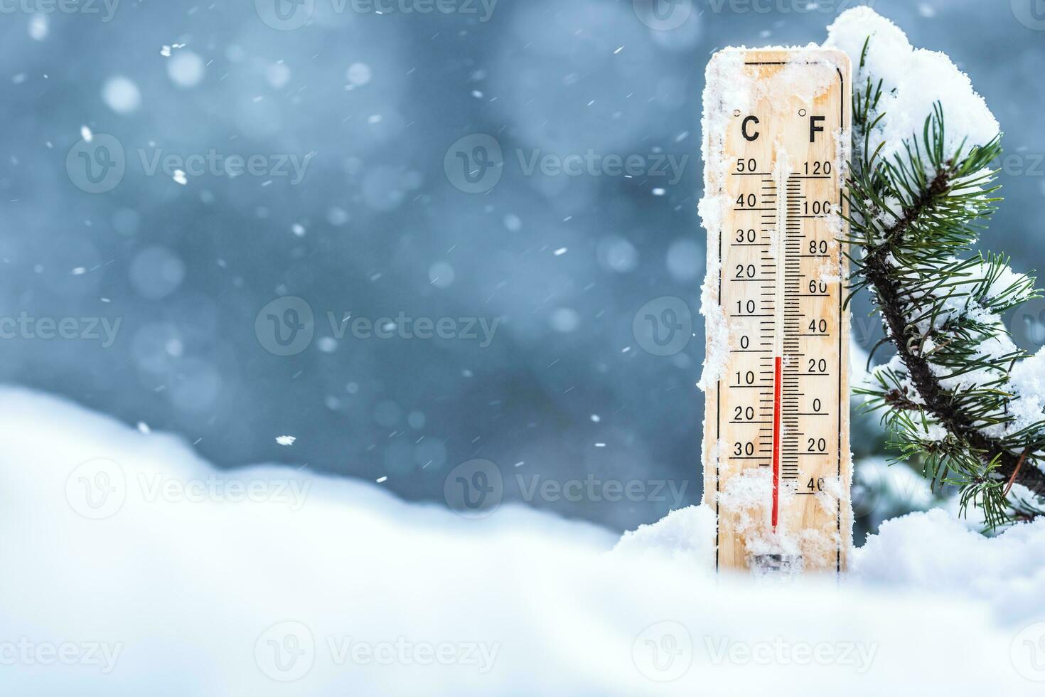 Thermometer on snow shows low temperatures in celsius or farenheit photo