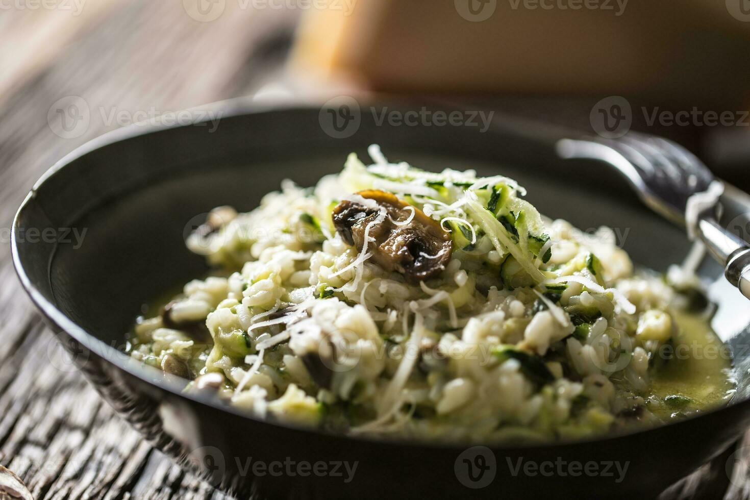 italiano risotto calabacín hongos y parmesano en oscuro plato foto