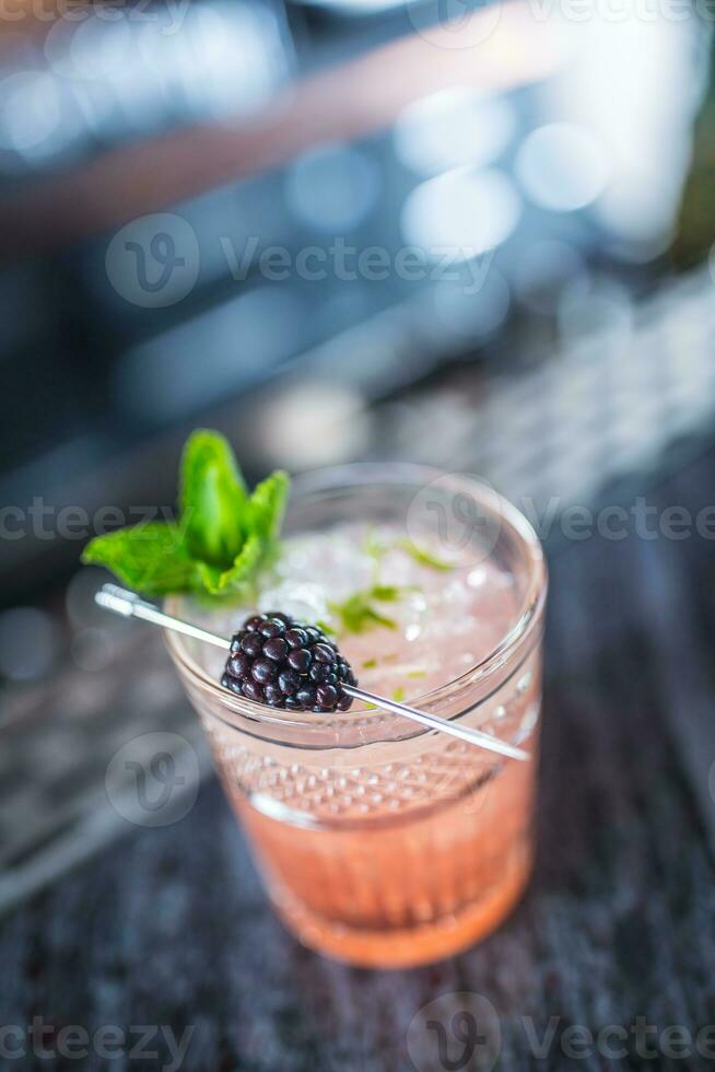 Cocktail drink bramble with black berries and mint at barcounter in night club or restaurant photo