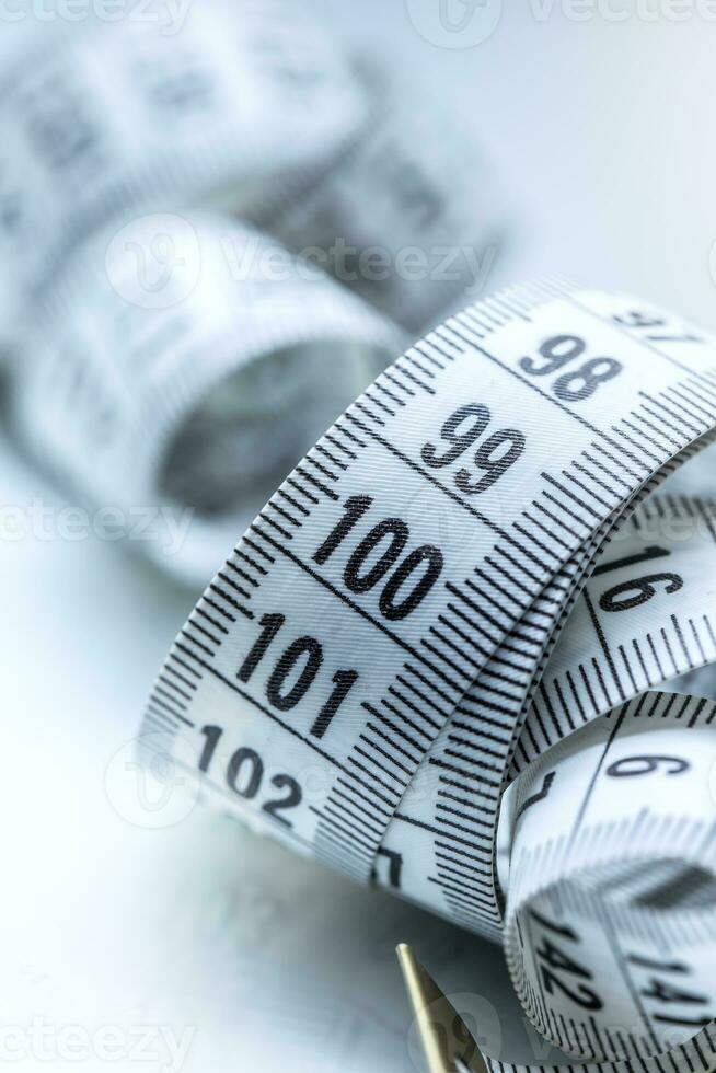 Curved measuring tape. Measuring tape of the tailor. Closeup view of white measuring tape photo