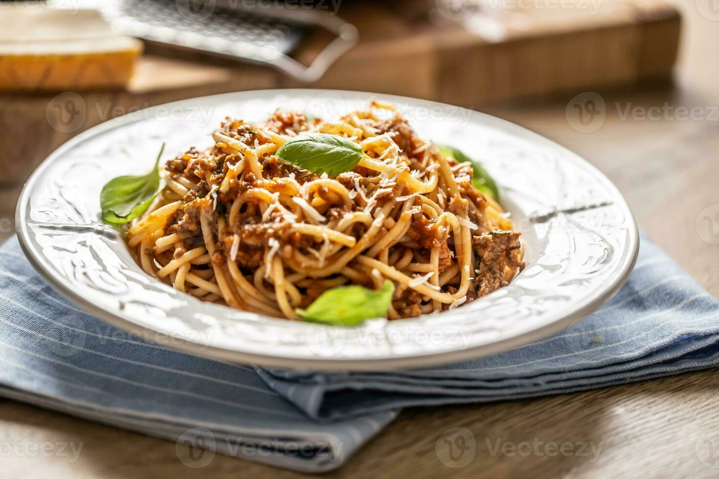 Italian pasta spaghetti bolognese served on white plate with parmesan cheese and basil photo