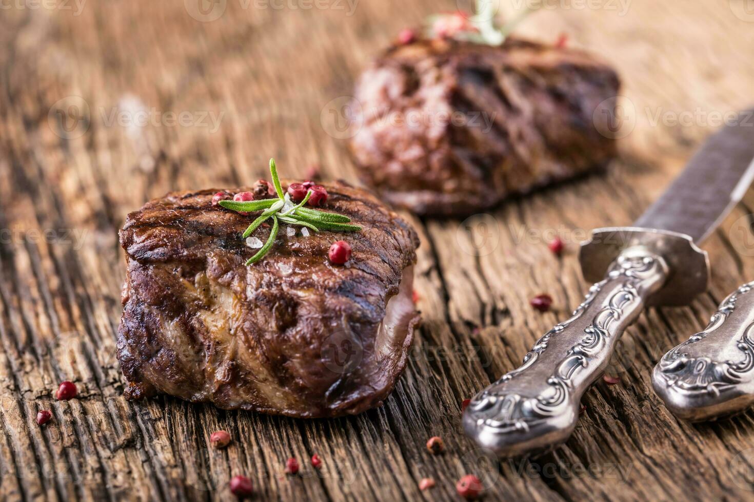 Grilled beef steak with rosemary, salt and pepper on old cutting board. Beef tenderloin steak. photo